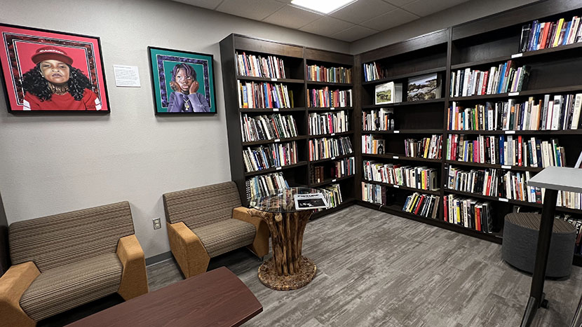 A wall of bookcases, two chairs and a reading table