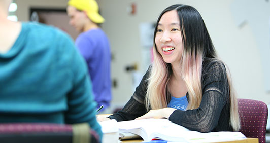 A female student talking with a textbook open