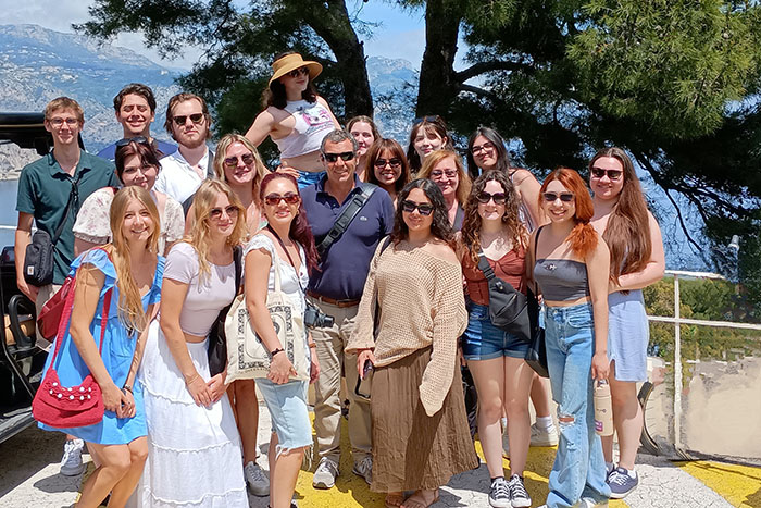 A group of students pose in front of a tree along the French Riviera