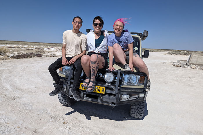 Three students on the hood of a truck in Namibia