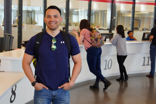 Student standing next to enrollment services counter