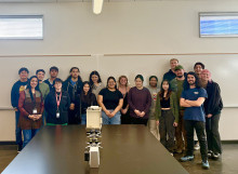 A group of students standing with a device on the table in front